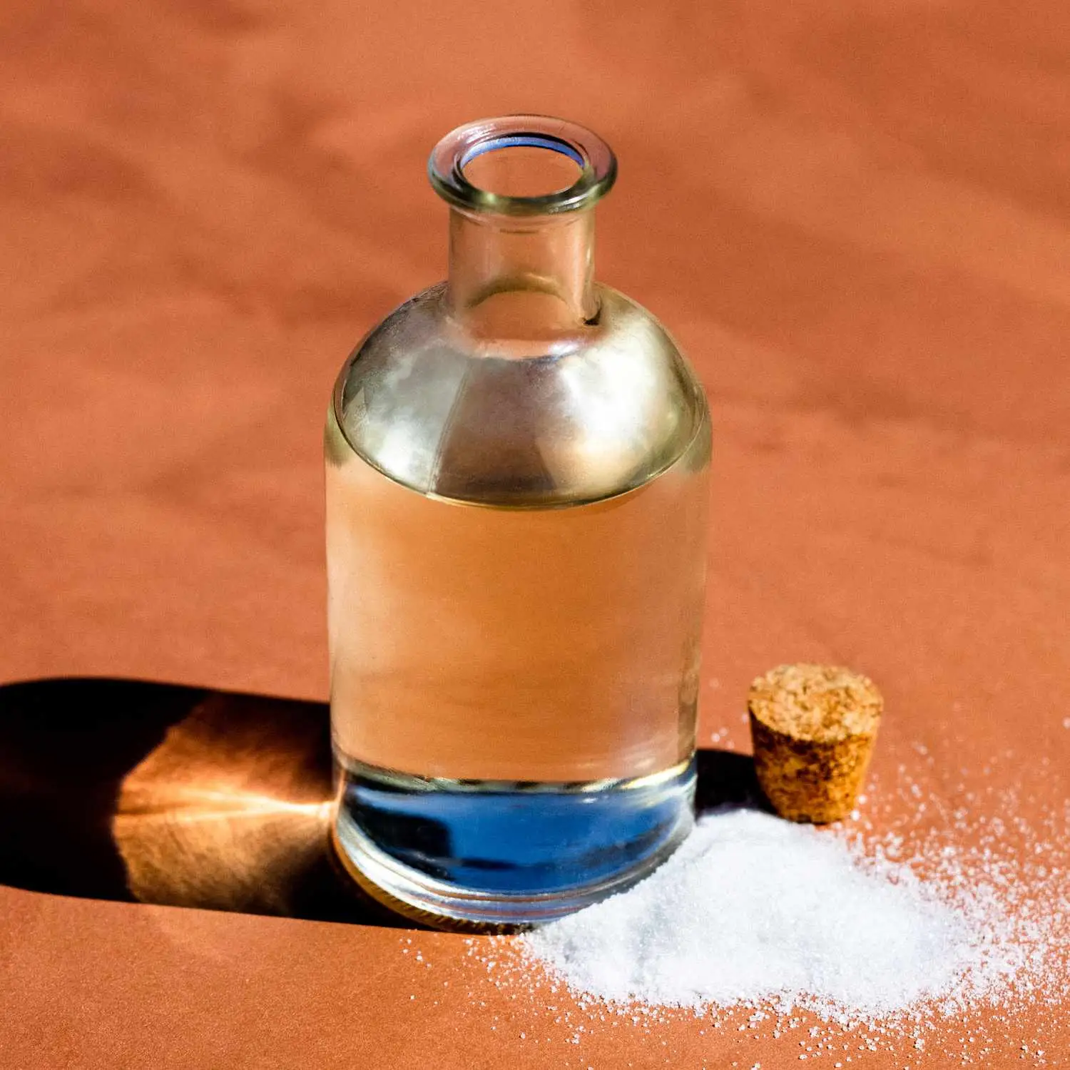 Simple Syrup in glass jar with cork stopper, next to a small pile of white sugar