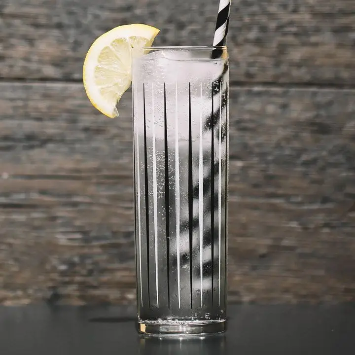 vodka soda cocktail with lemon wedge and black-and-white-striped straw
