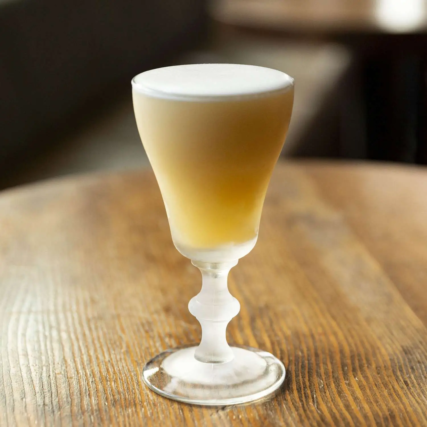 Stone Fruit Sour in footed Irish Coffee glass with thick layer of egg white foam on top