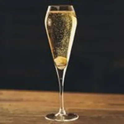 My Golden Dram cocktail in a Champagne flute with a sugar cube at bottom and tiny bubbles floating upward, served on wooden surface