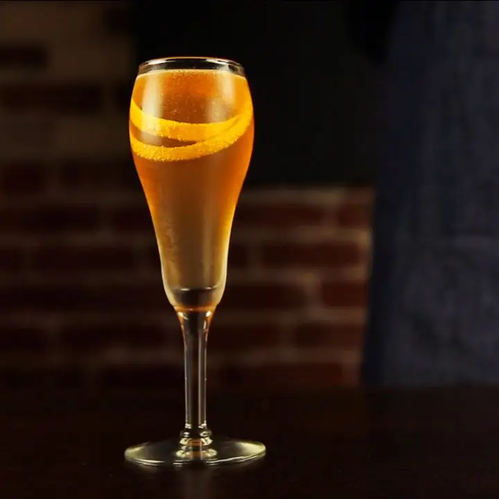 Seelbach Cocktail in a flute with a long orange twist wrapped inside the glass