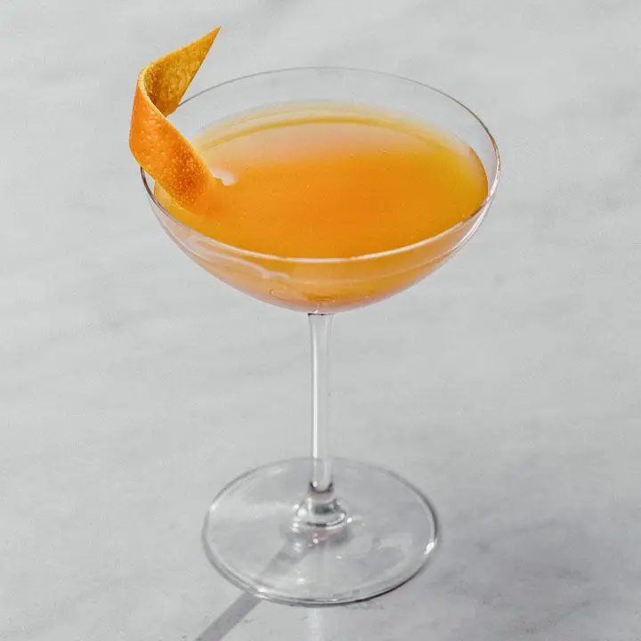 orange-colored Roosevelt cocktail in a cocktail glass, garnished with an orange twist