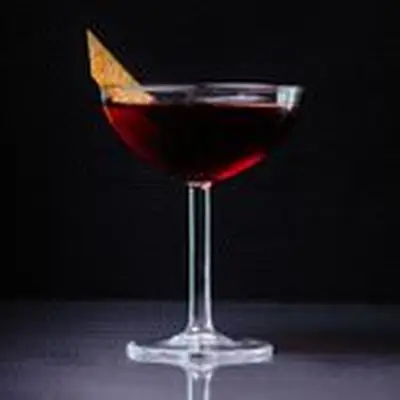 A Martinez cocktail in a coupe glass garnished with orange zest