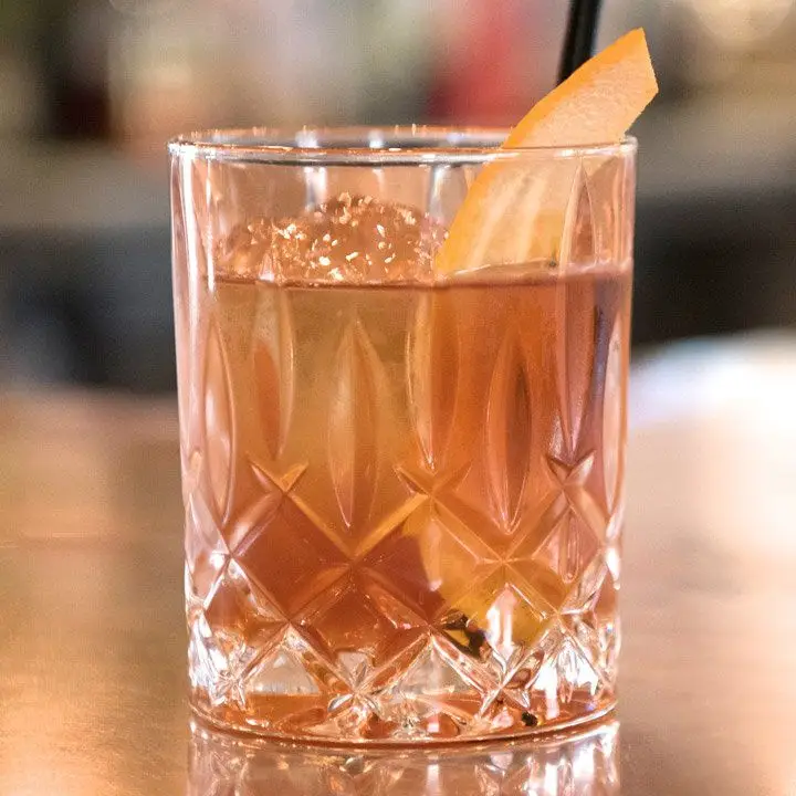 Expense of Honesty cocktail in a crystal-cut rocks glass with an orange peel garnish