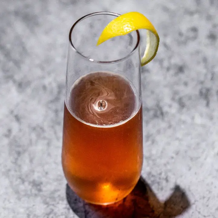 Cowboy Coffee cocktail in a half-filled stemless flute, with a lemon twist balanced on the rim