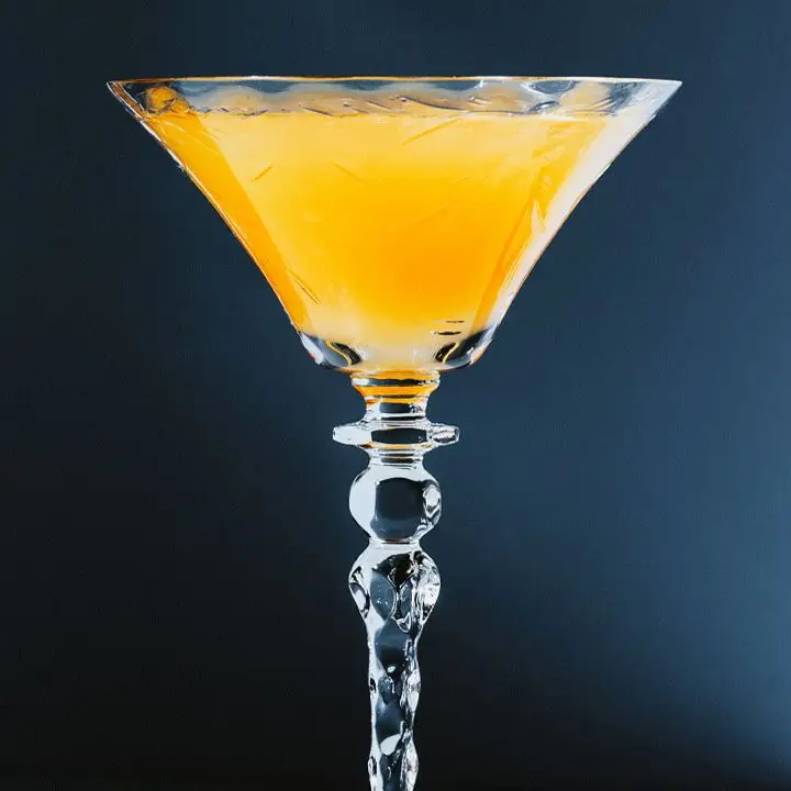 orange-colored Pineapple Upside Down Cake cocktail in a cocktail glass