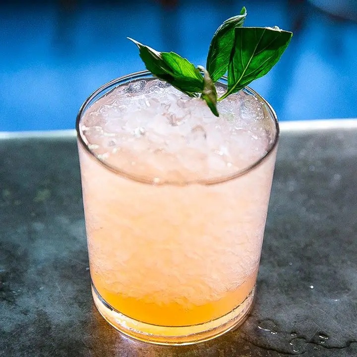 Aquarelle cocktail in a rocks glass, served over crushed ice and garnished with a basil sprig