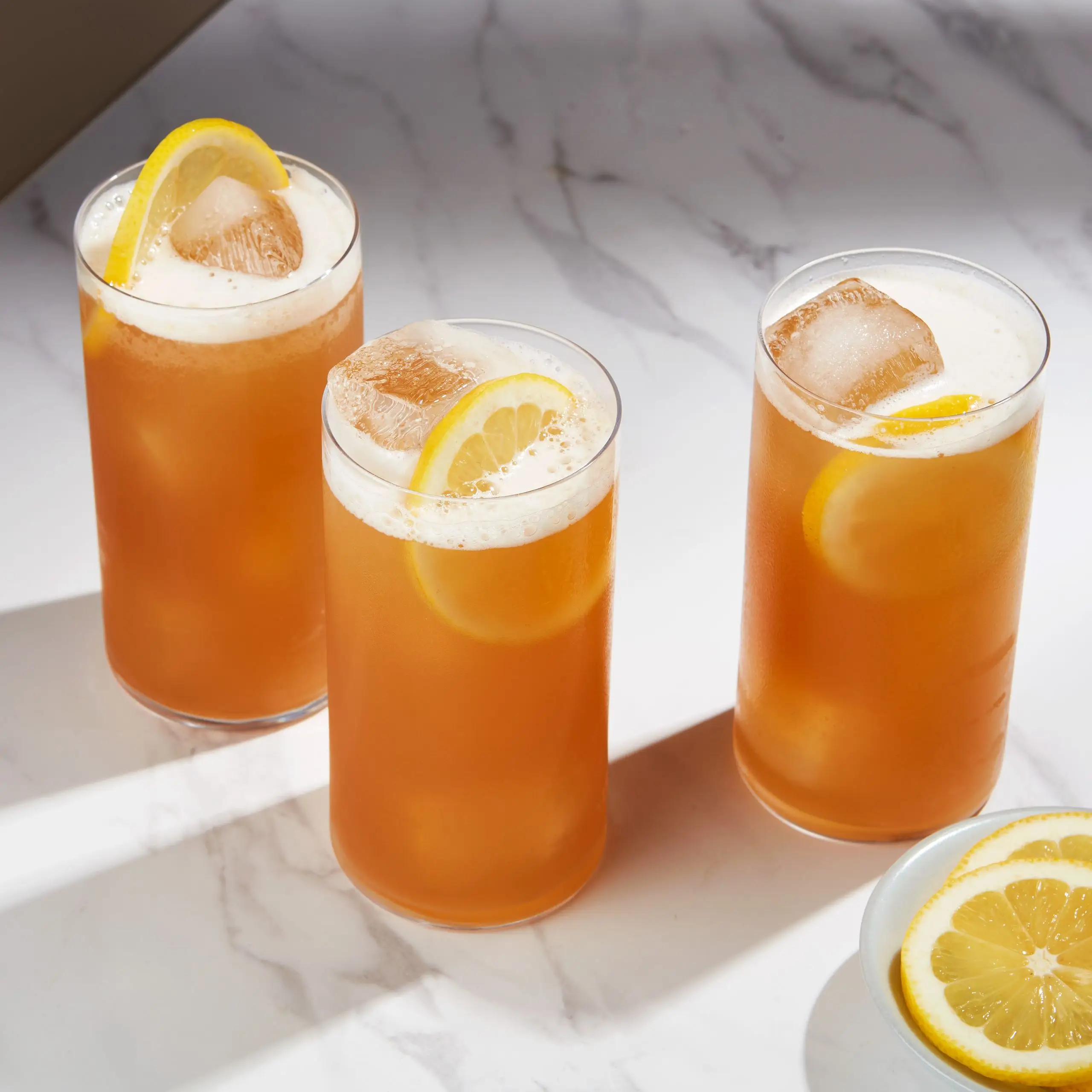 Two Bizzy Izzy Cocktails on a counter with lemon slices.