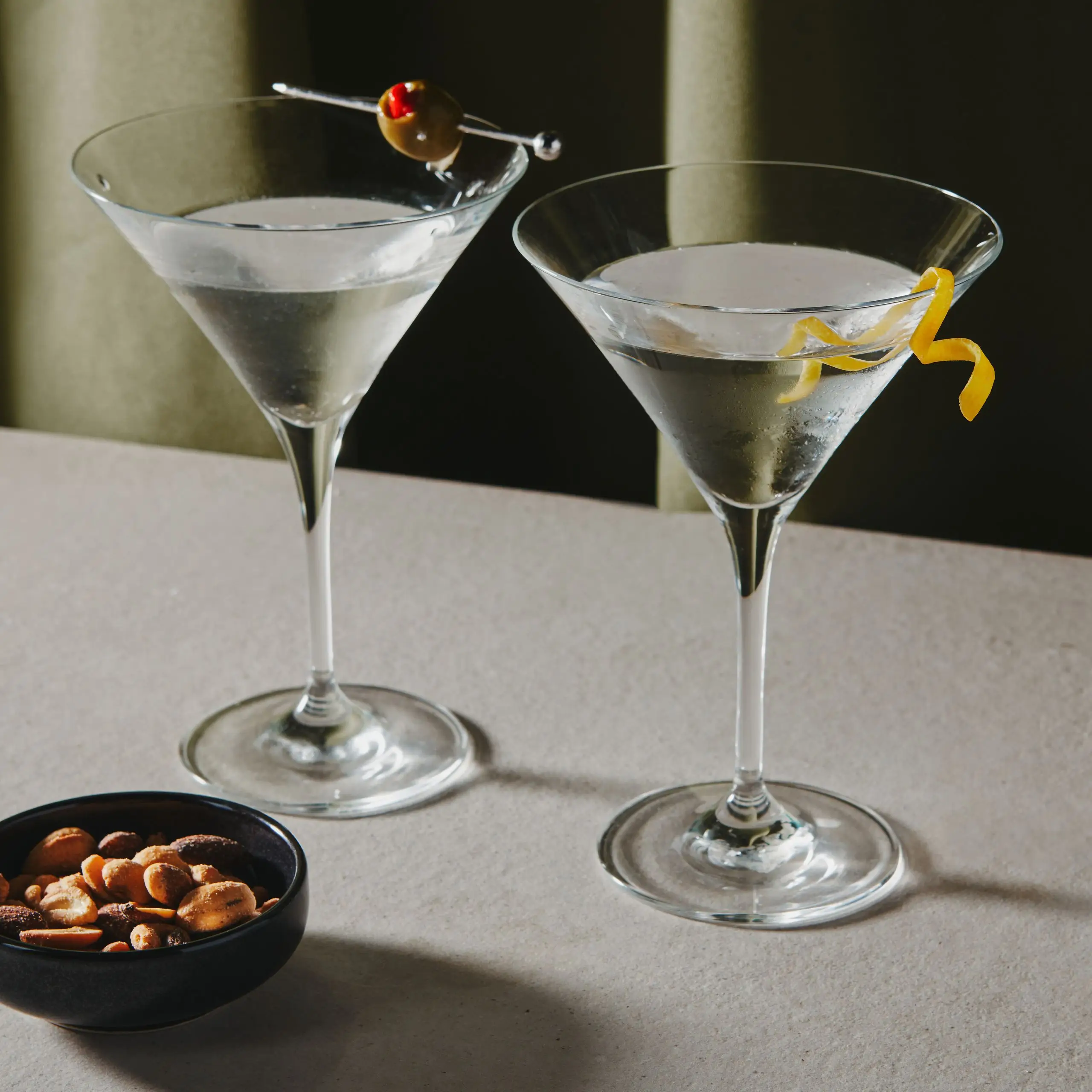 One Vodka Martini garnished with an olive and another garnished with a lemon twist.