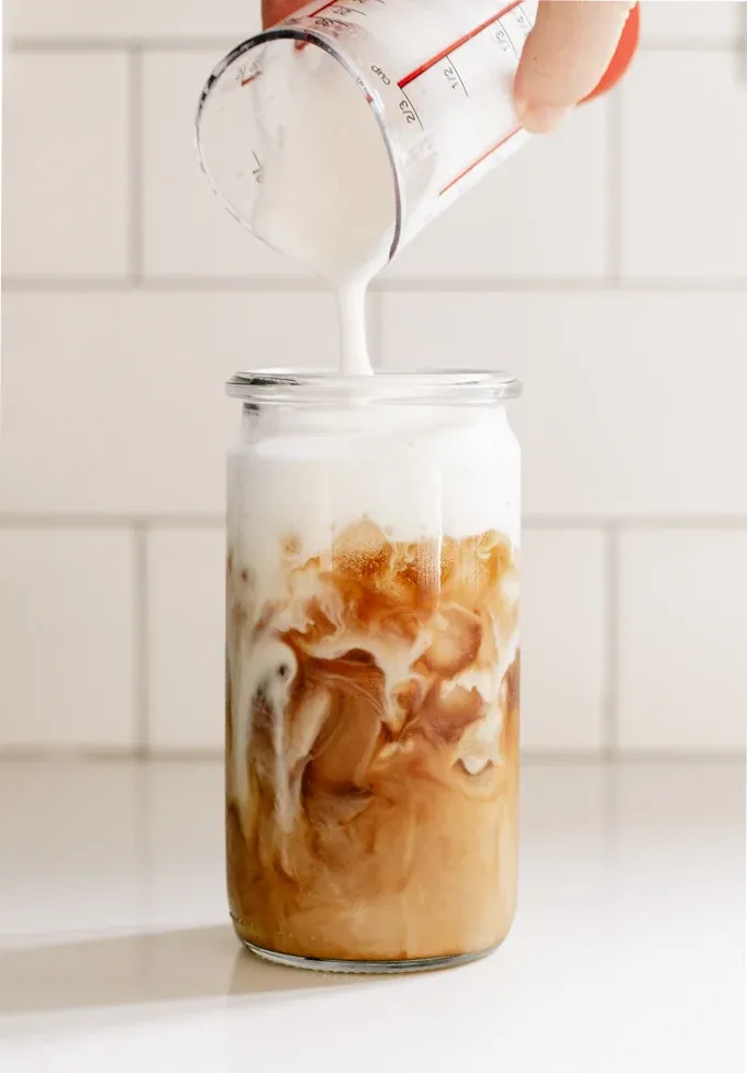 Pouring cold foam over iced coffee. ' title='Sweet Cream Cold Foam Recipe