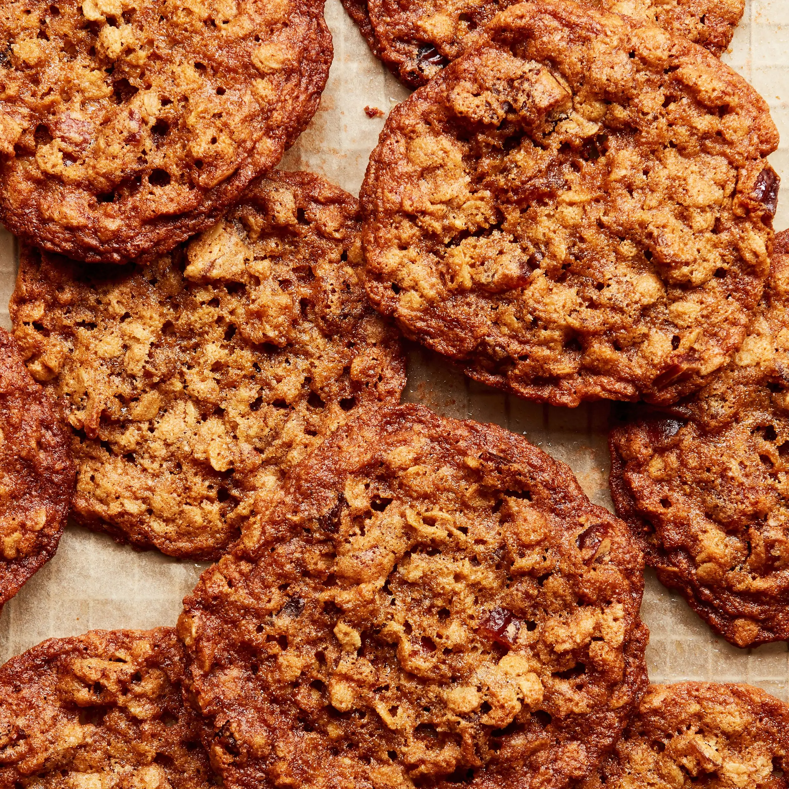 Photo of oatmeal date cookies on a piece of parchment paper on a cooling rack.