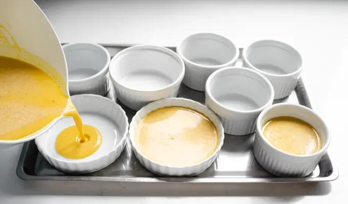 Pouring the pumpkin custard into ramekins. ' title='Easy Baked Pumpkin Custard with Nutmeg Whipped Cream