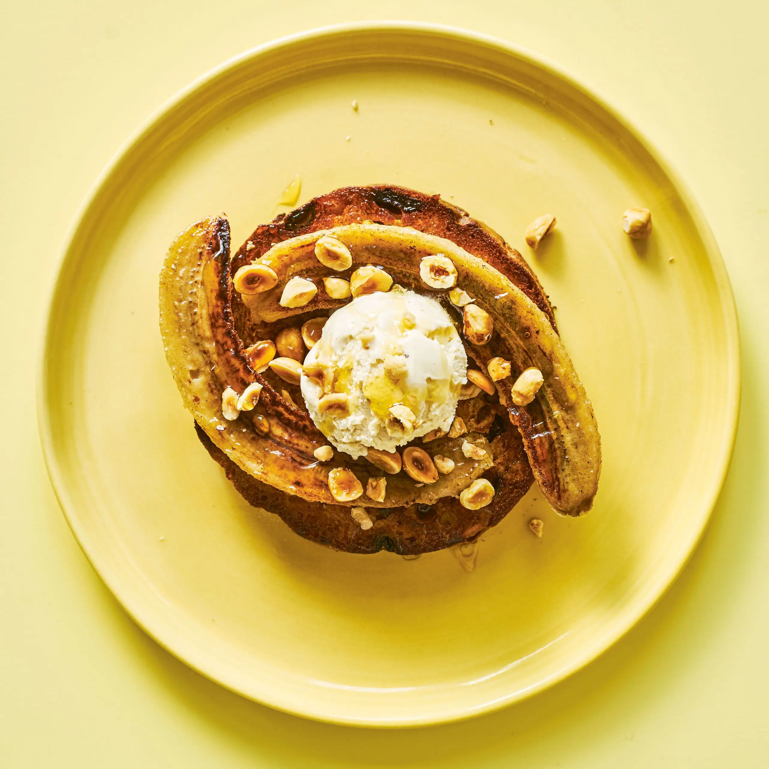 Bananas Hazelnuts and Ice Cream with Brandy Syrup on Panettone on a yellow plate.