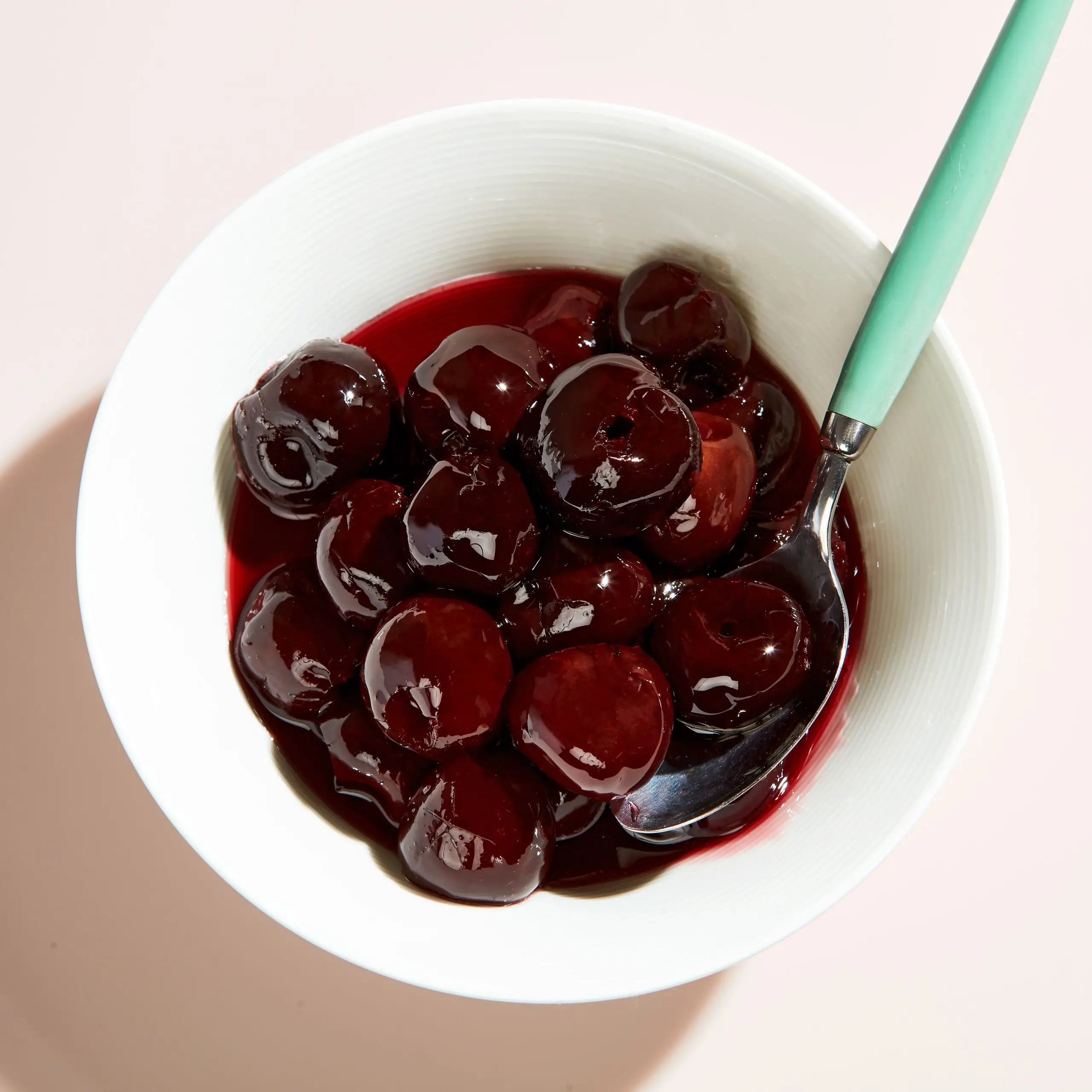 Homemade sundae cherries in a bowl with a spoon.