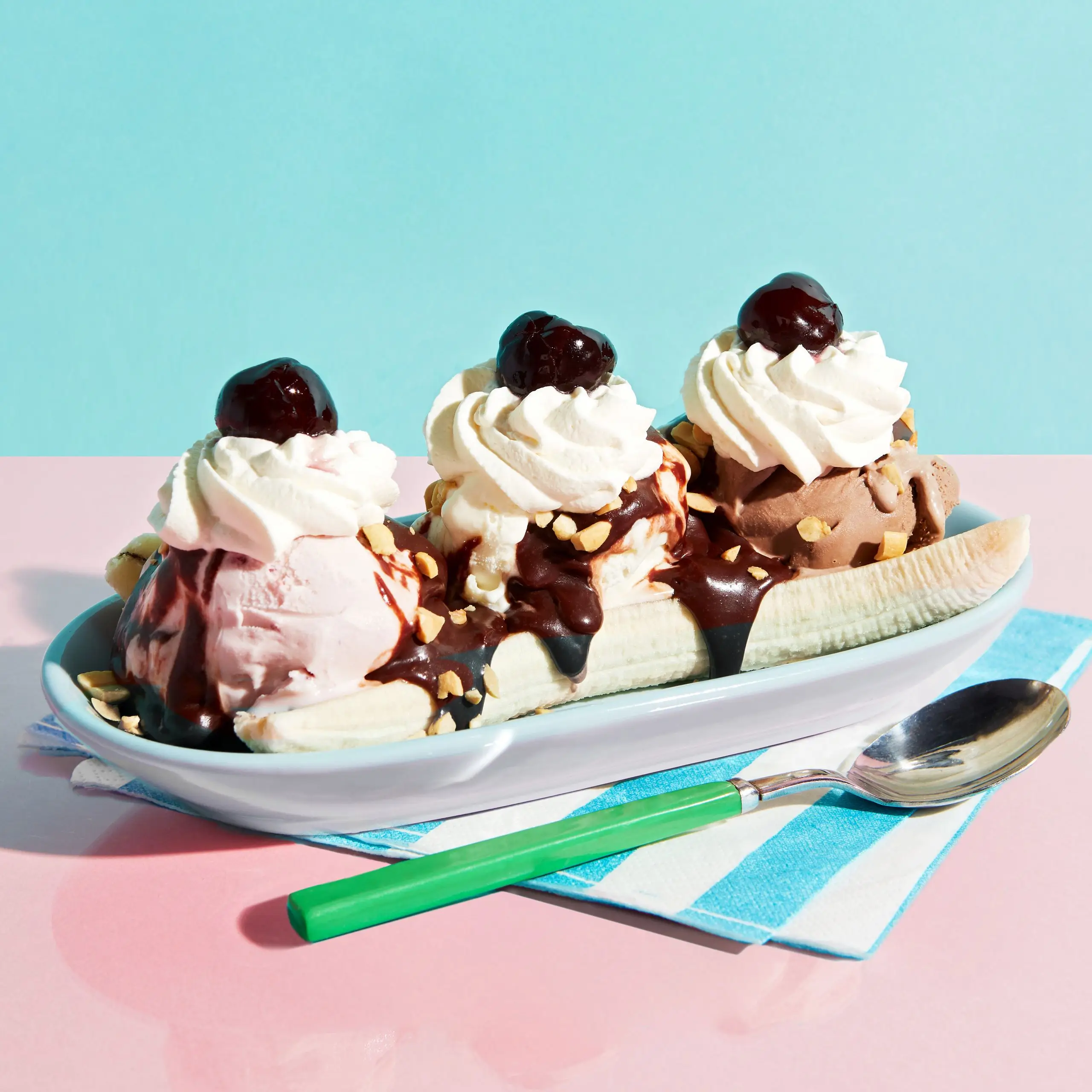 Scoops of strawberry vanilla and chocolate ice cream in a serving dish topped with whipped cream cherries nuts and bananas.