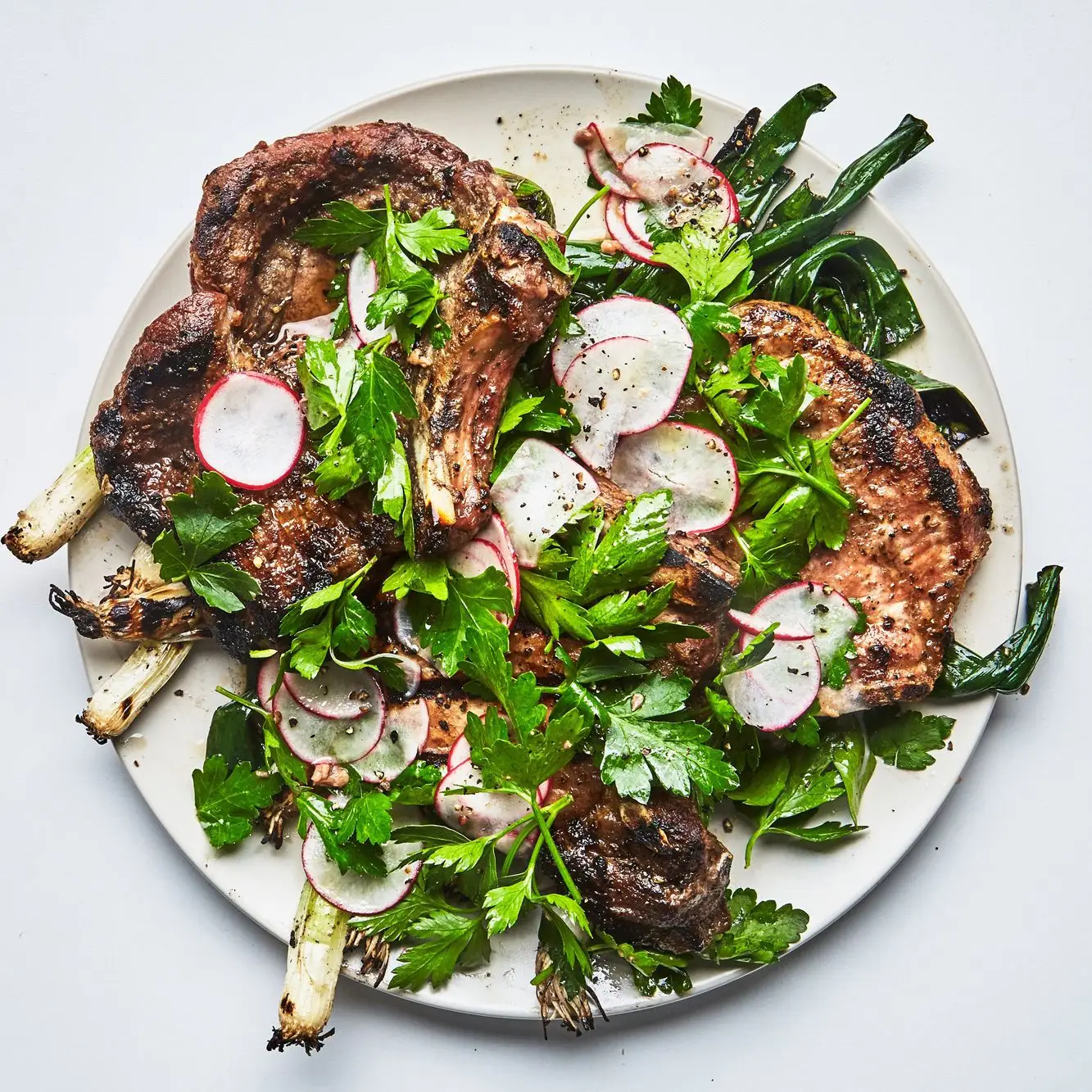 Costeletas de porco com rabanetes e cebolinhas carbonizadas