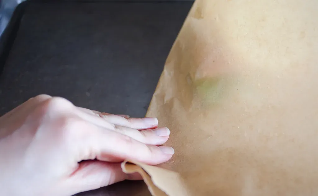 Creasing the piece of parchment paper on the baking sheet.' title='Salmon en Papillote