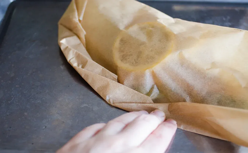 Making small folds along the edge of the piece of parchment paper to seal the salmon en papillote. ' title='Salmon en Papillote