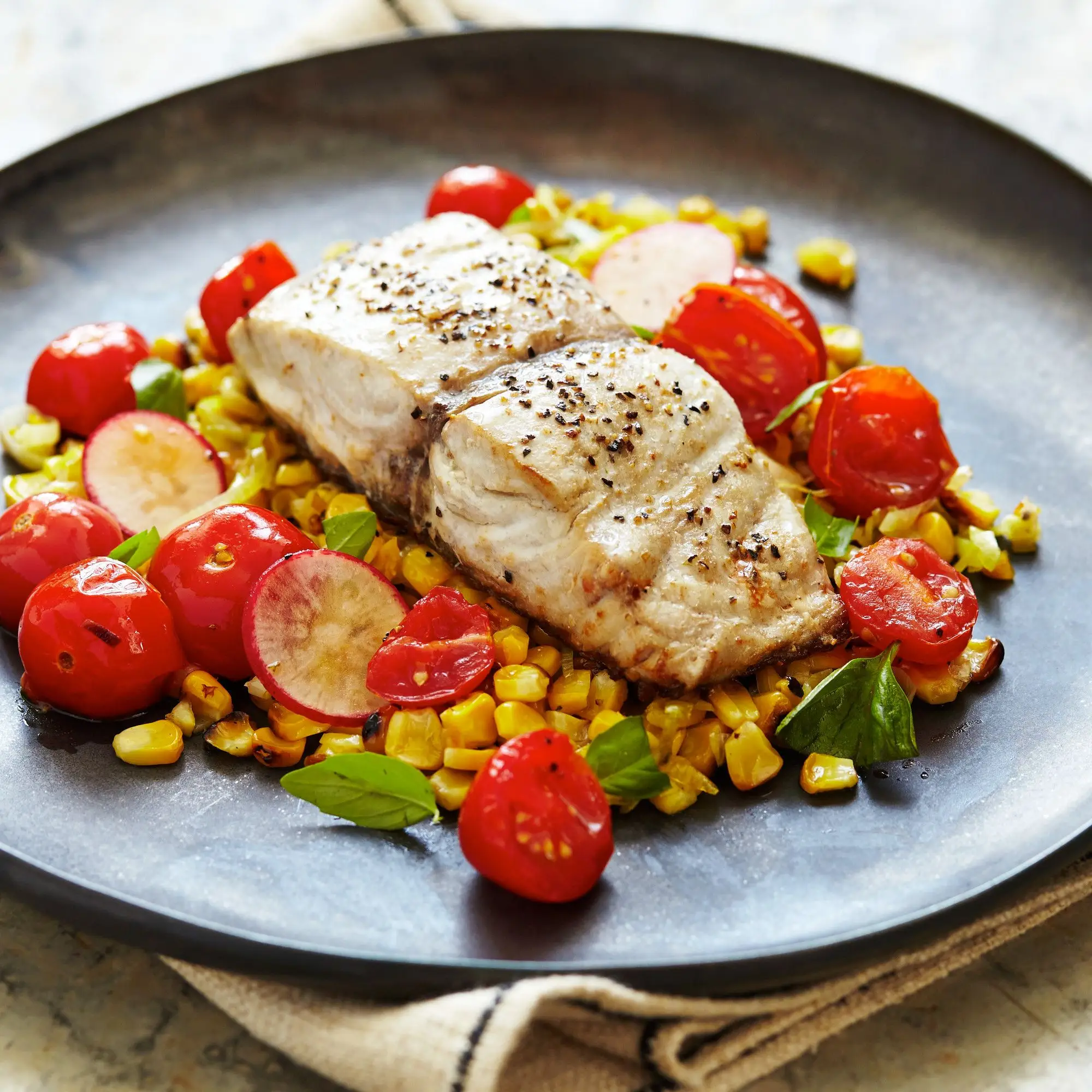 Peixe azul queimado com milho carbonizado, salada de tomate quente