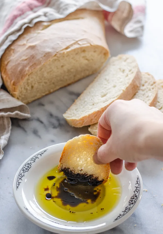 Dipping a slice of soft sourdough bread into a dish of olive oil and balsamic vinegar.' title='Soft Sourdough French Bread Without Yeast!