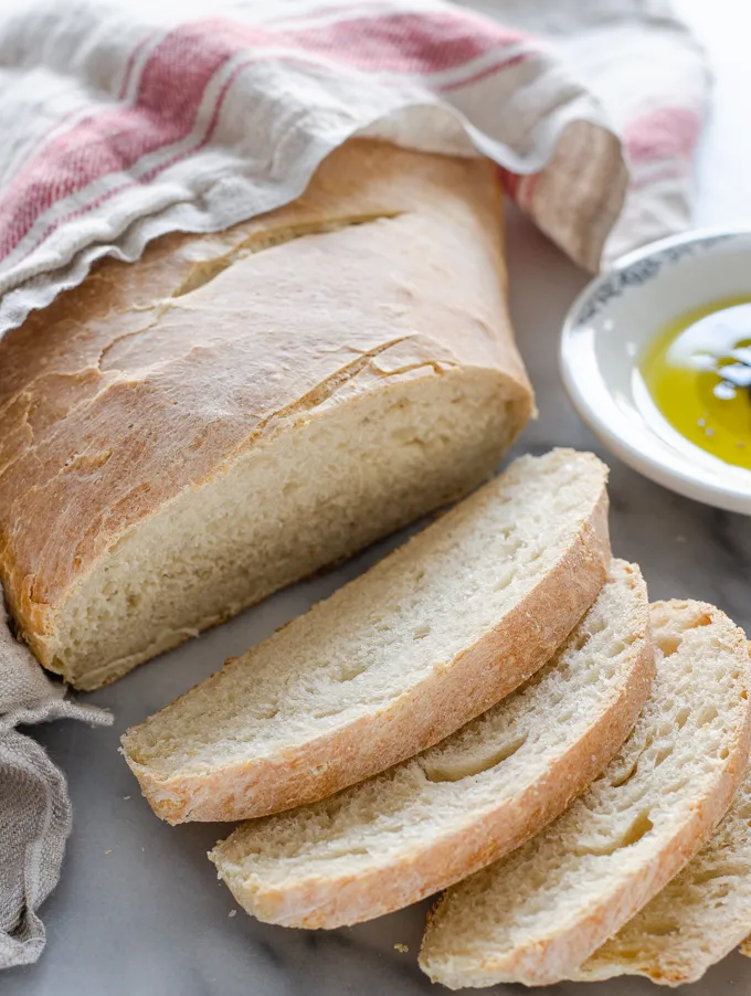 A sliced loaf of Soft Sourdough French Bread No Yeast all baked with a dish of olive oil and vinegar in the background.' title='Soft Sourdough French Bread Without Yeast!
