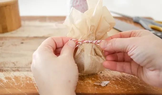 Tying bakers twine around the parchment paper packet.' title='How to Roast Garlic Without Aluminum Foil