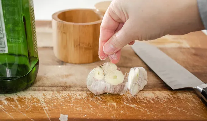 Sprinkling salt on the head of garlic before roasting it.' title='How to Roast Garlic Without Aluminum Foil