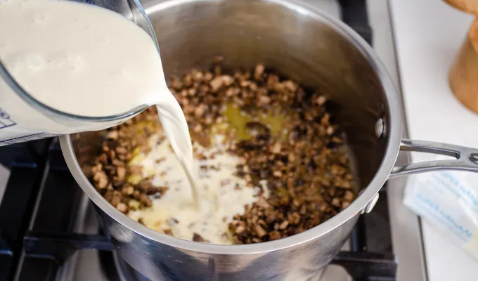 Adding the cream and cornstarch mix to the mushrooms and onions.' title='Gluten Free Cheesy Potatoes