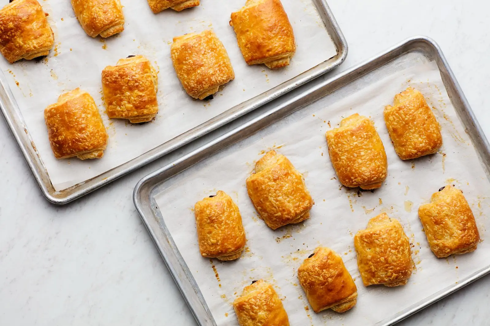 Baked chocolate croissants on sheet pans.