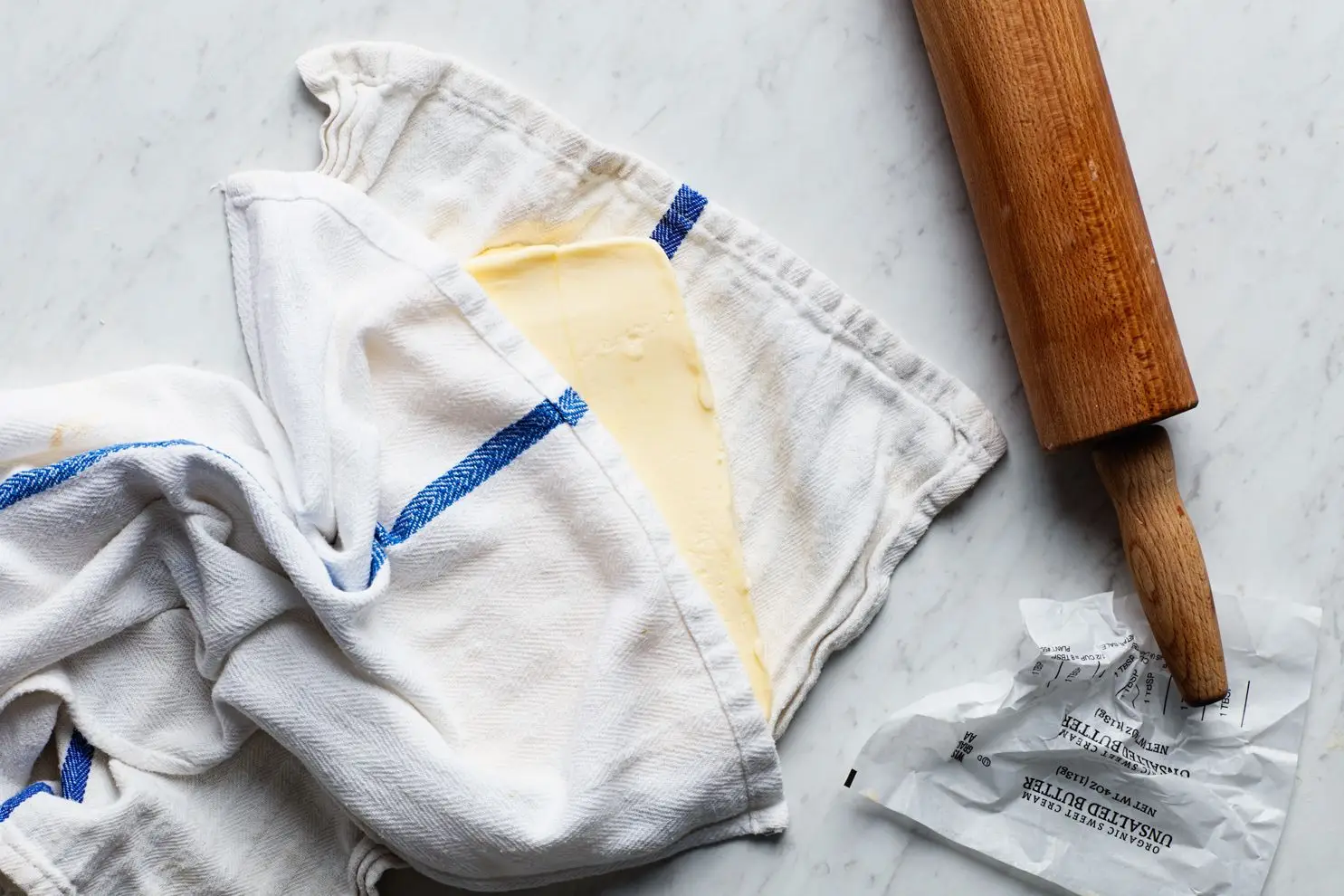 A butter block for laminated dough in a kitchen towel.