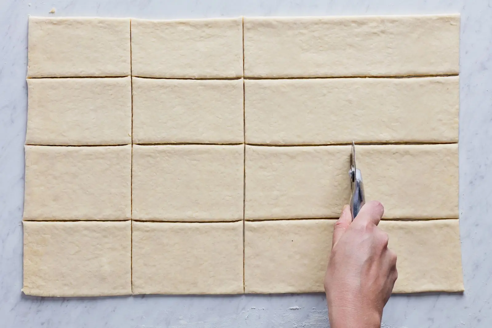 Rolledout croissant dough being portioned into a 44 grid.