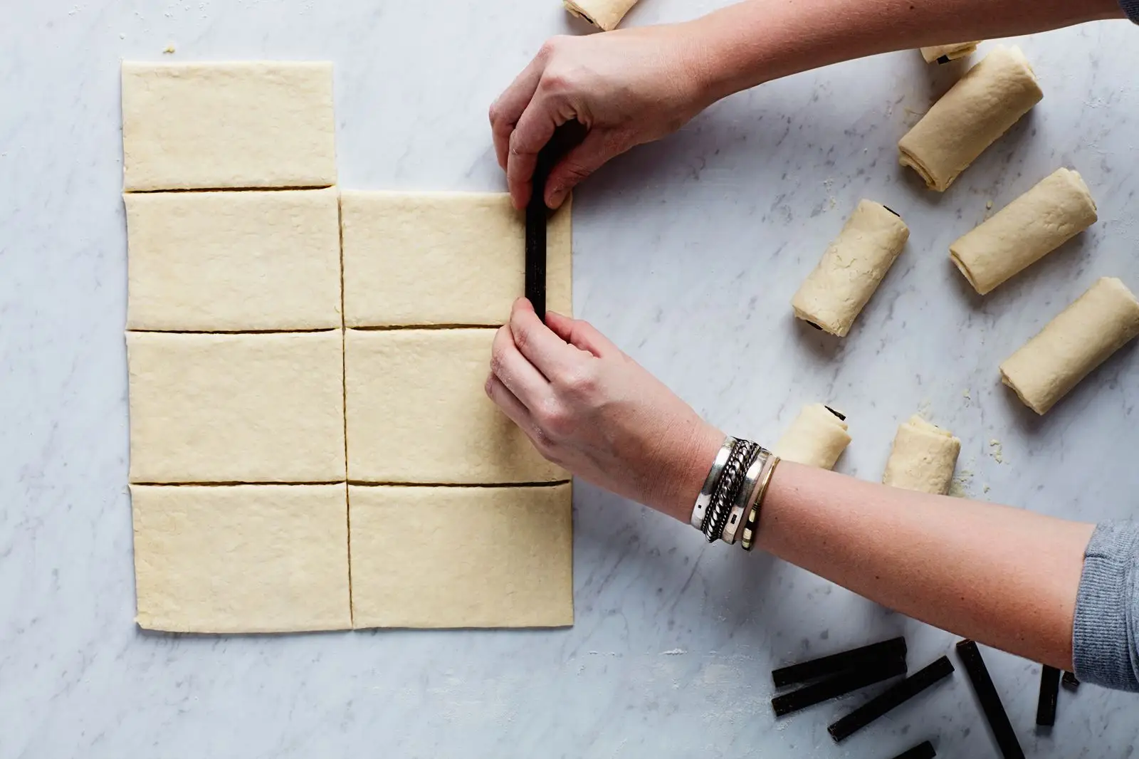 Rolling chocolate batons into rectangles of laminated yeast dough.