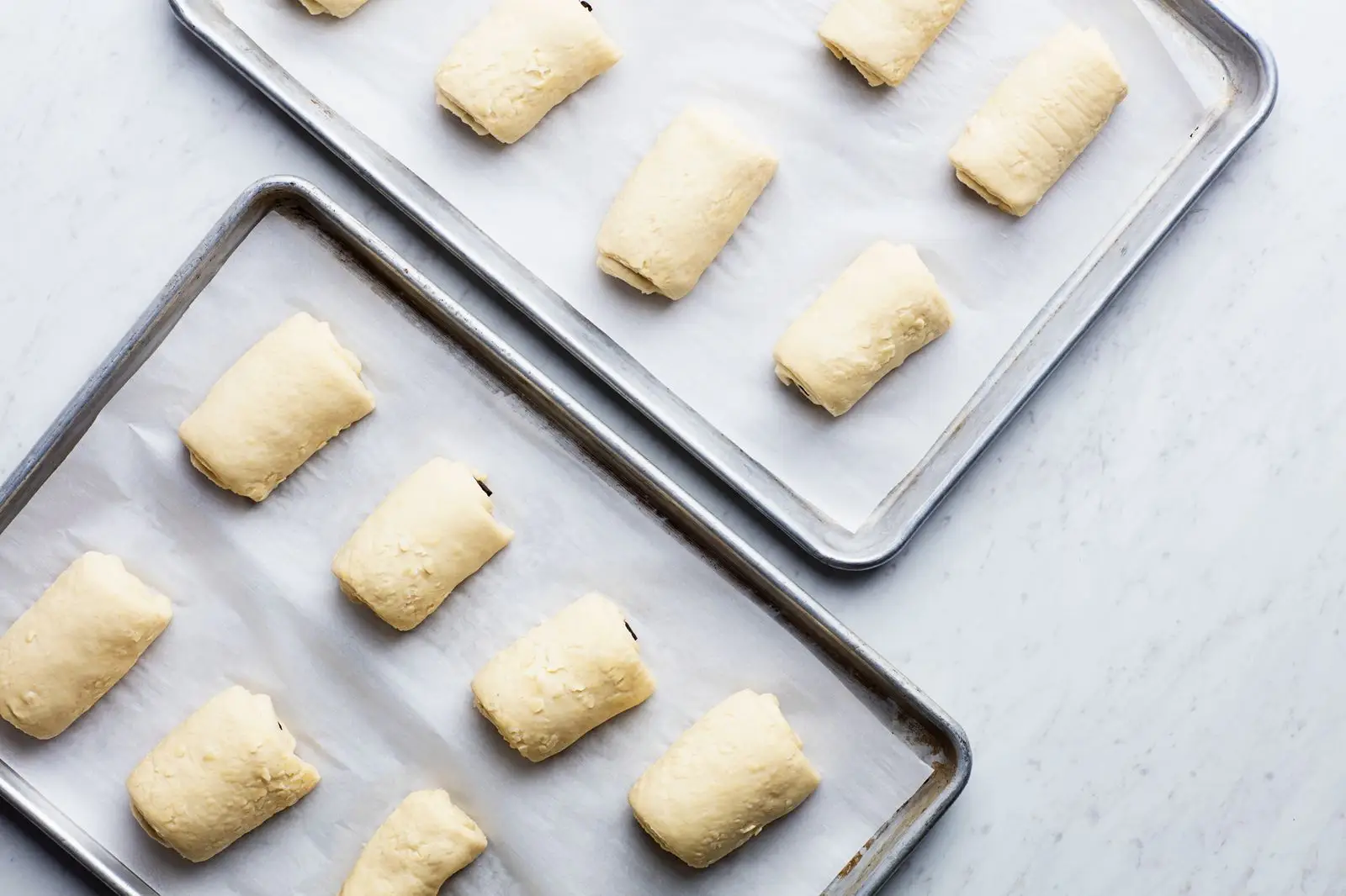 Chocolate croissants rising on sheet pans.