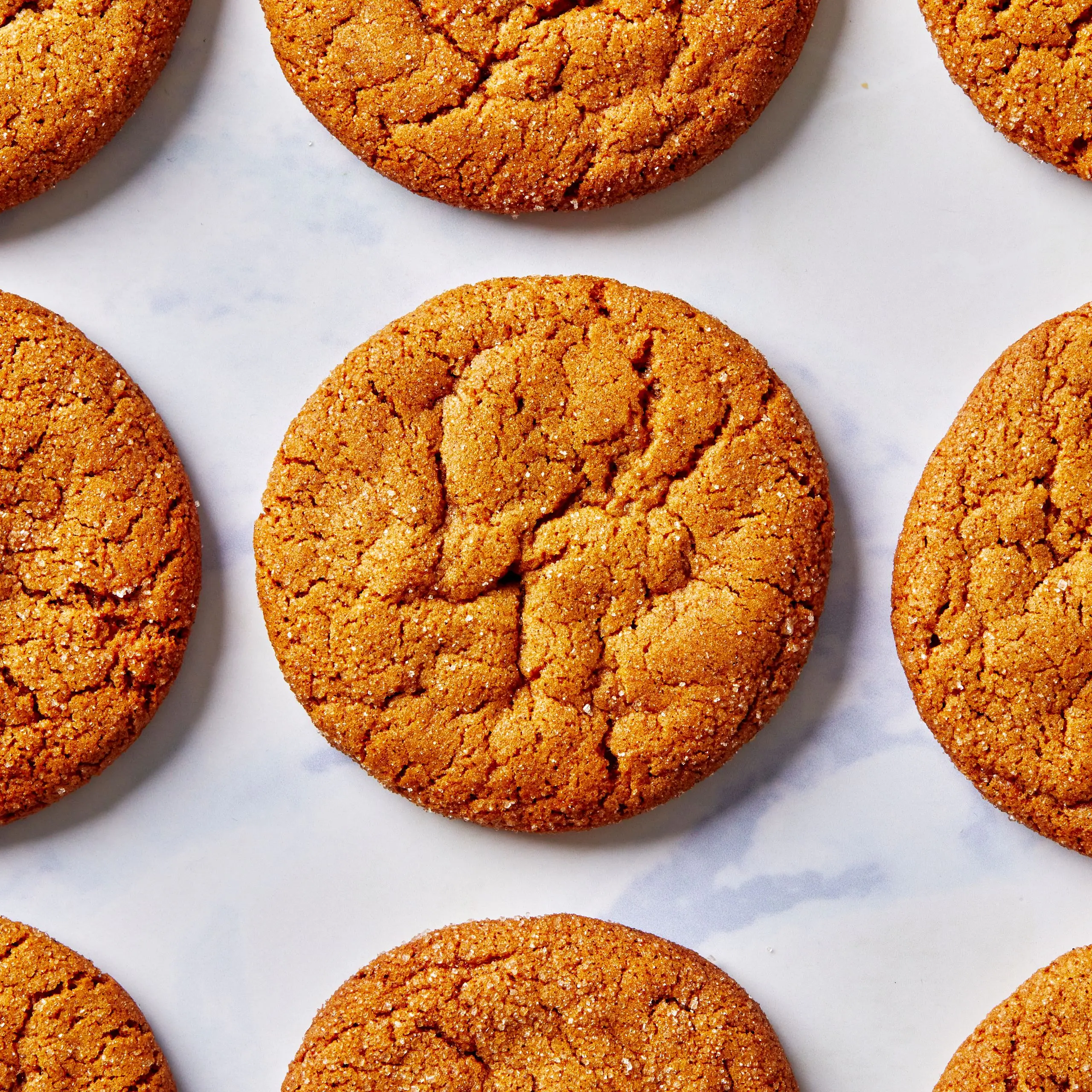 Grid of soft molasses cookies as seen from overhead atop marble surface.