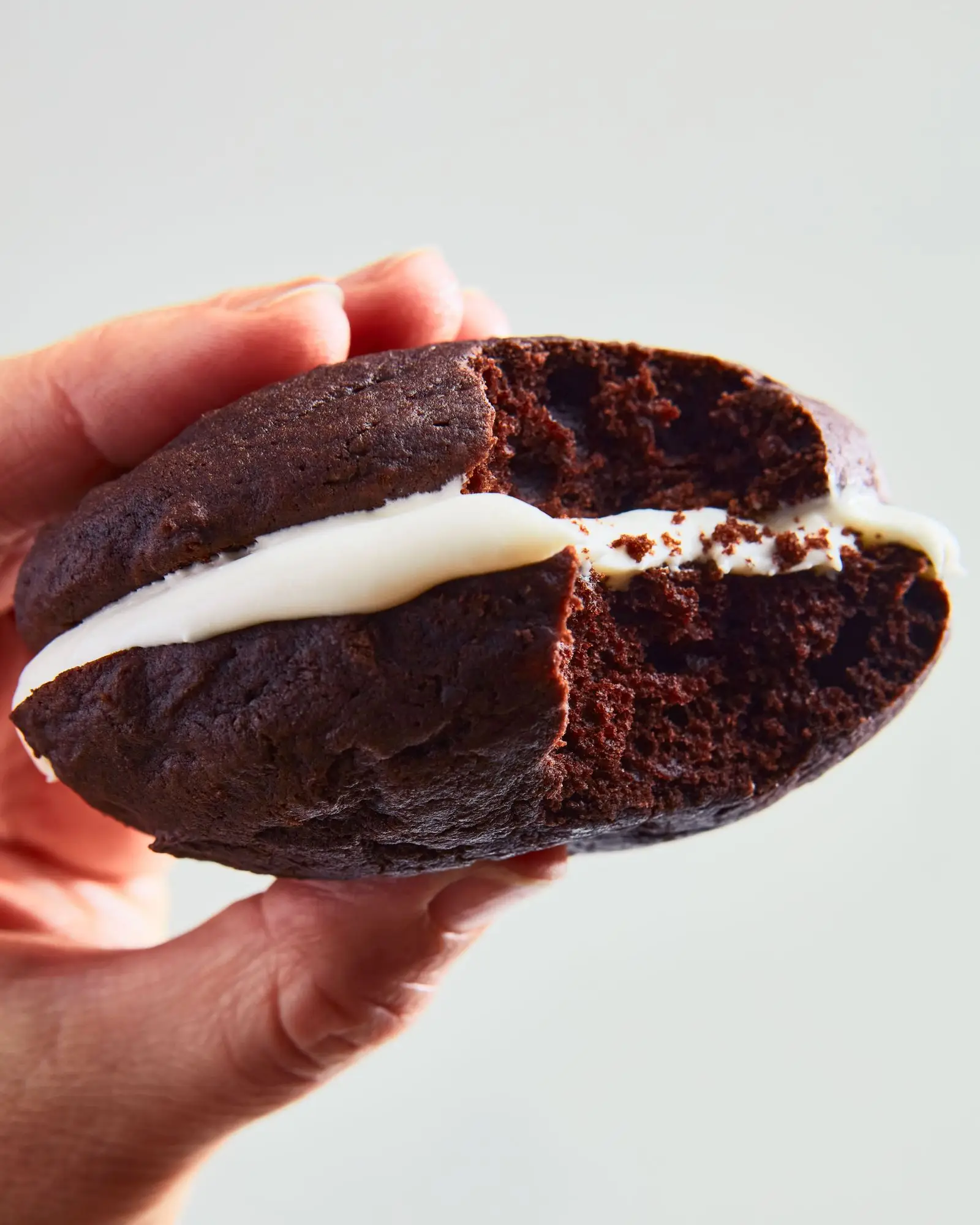 A chocolate cookie filled with marshmallow fluff with a bite taken out.