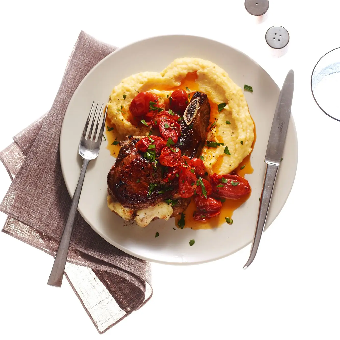 Costeleiros de porco com polenta e tomate