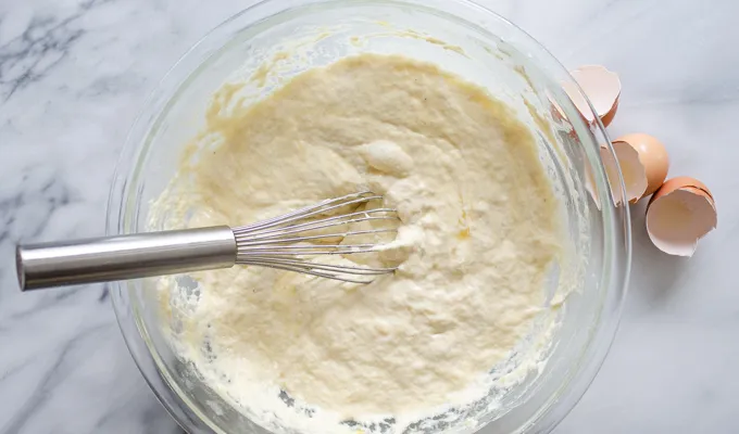 The bowl of batter on a marble surface with a whisk in it.' title='The Best Sourdough Pancakes