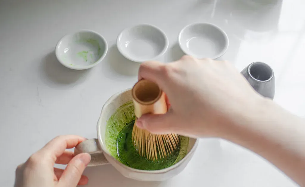 Whisking the matcha and sugar with hot water in a stoneware mug with a bamboo matcha whisk (chasen).' title='Starbucks Hot Matcha Green Tea Latte Recipe