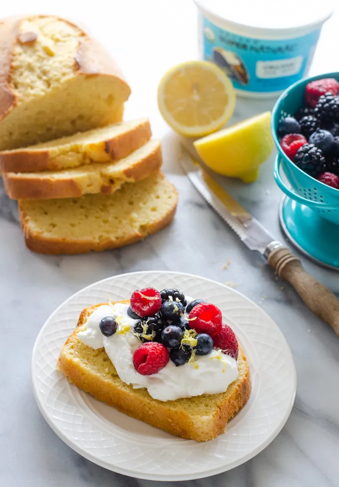 A slice of sour cream pound cake loaf topped with whipped cream and berries.' title='Sour Cream Pound Cake Loaf