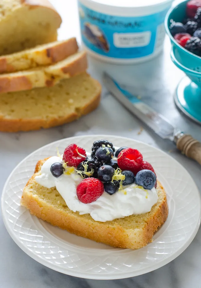 A slice of sour cream pound cake loaf topped with whipped cream and berries.' title='Sour Cream Pound Cake Loaf