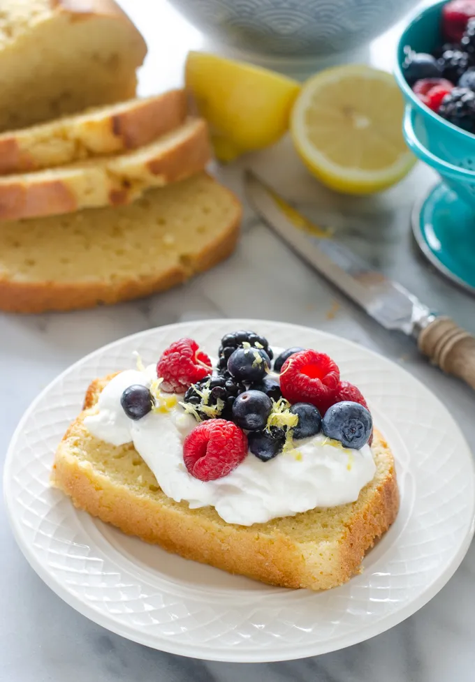A slice of sour cream pound cake loaf topped with whipped cream and berries.' title='Sour Cream Pound Cake Loaf