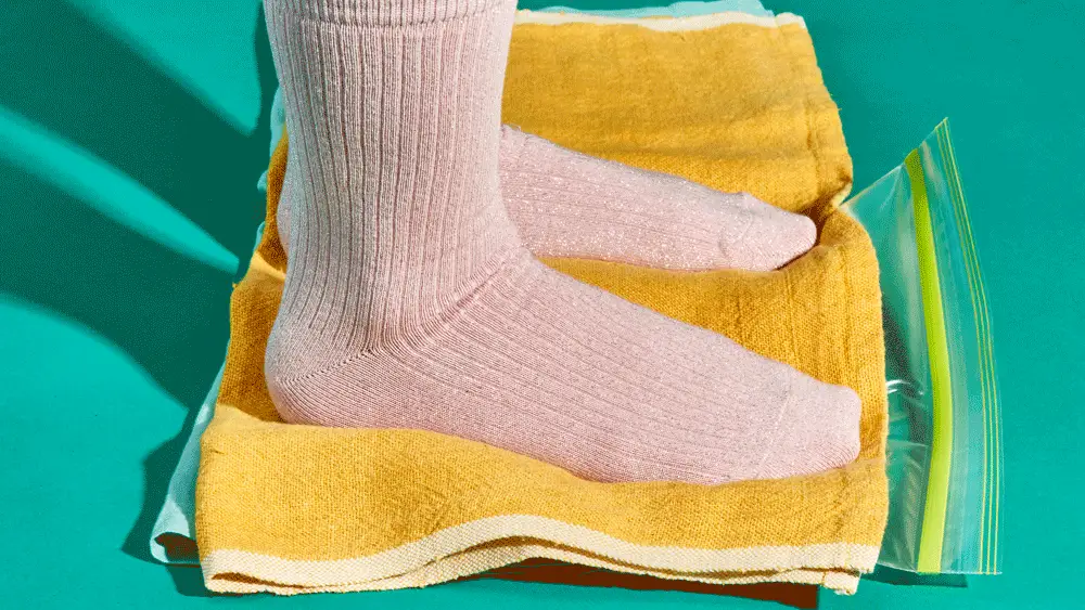 Two feet in pink socks stomping on a bag of dough.