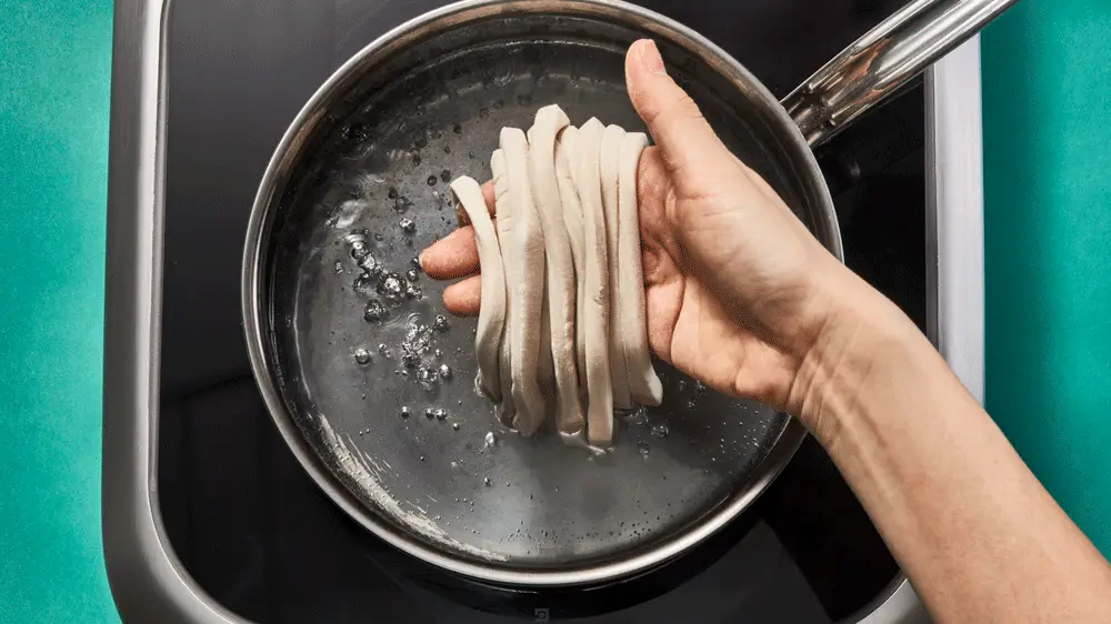 Noodles being dropped into boiling water.