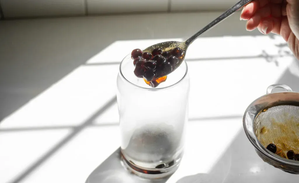 Placing the cooked tapioca pearls into a glass.' title='How to Make Matcha Milk Tea with Boba