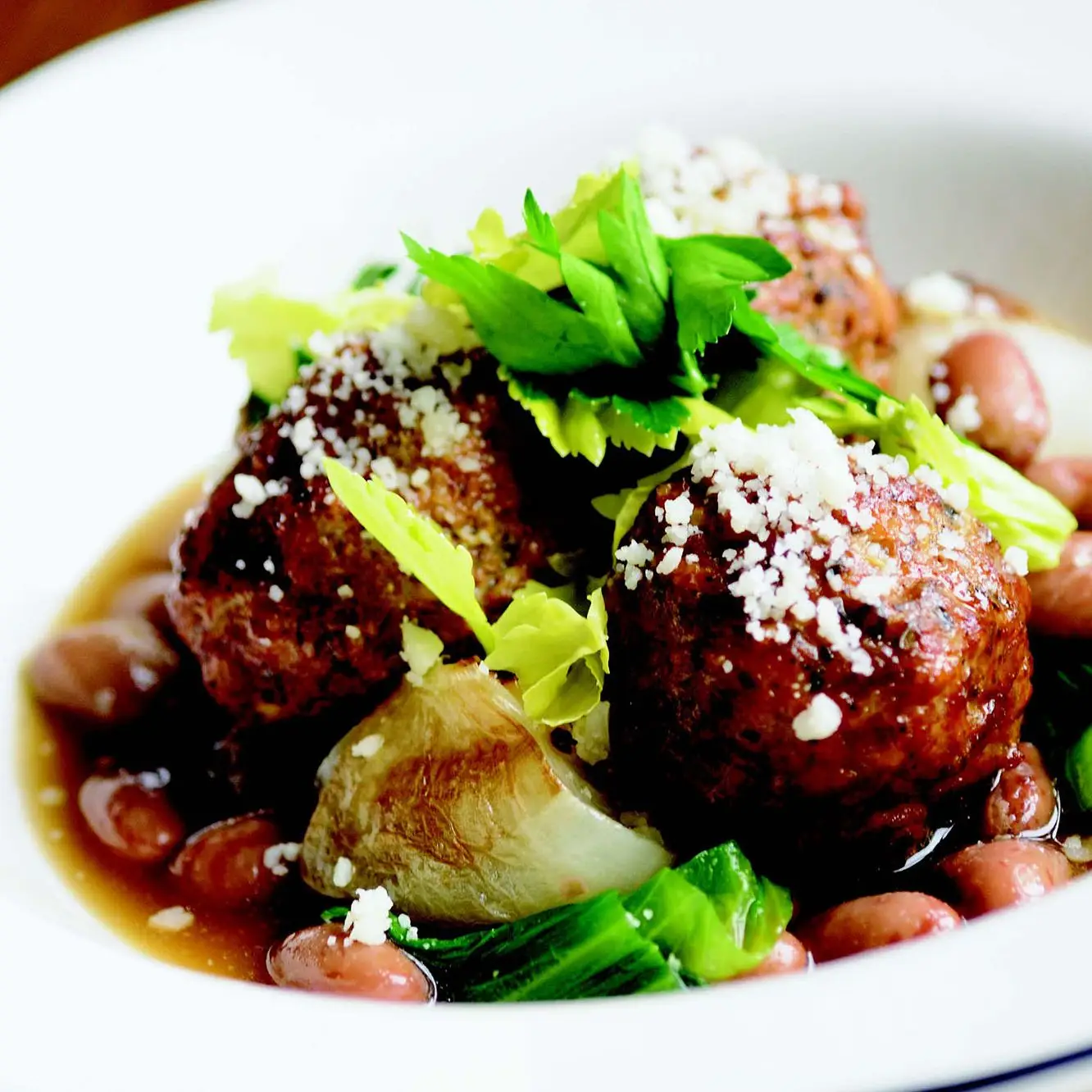 Almôndegas de cordeiro com escarola, cebolinha cipollini e feijão de cranberry