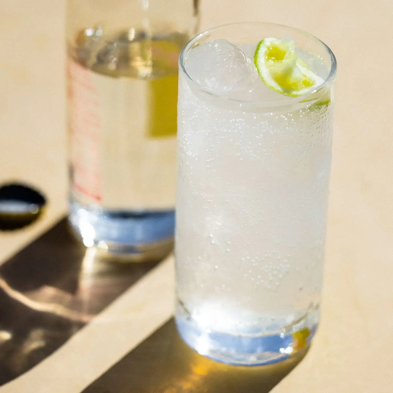 Ranch Water cocktail served in highball glass with lime wedge, Topo Chico bottle in background