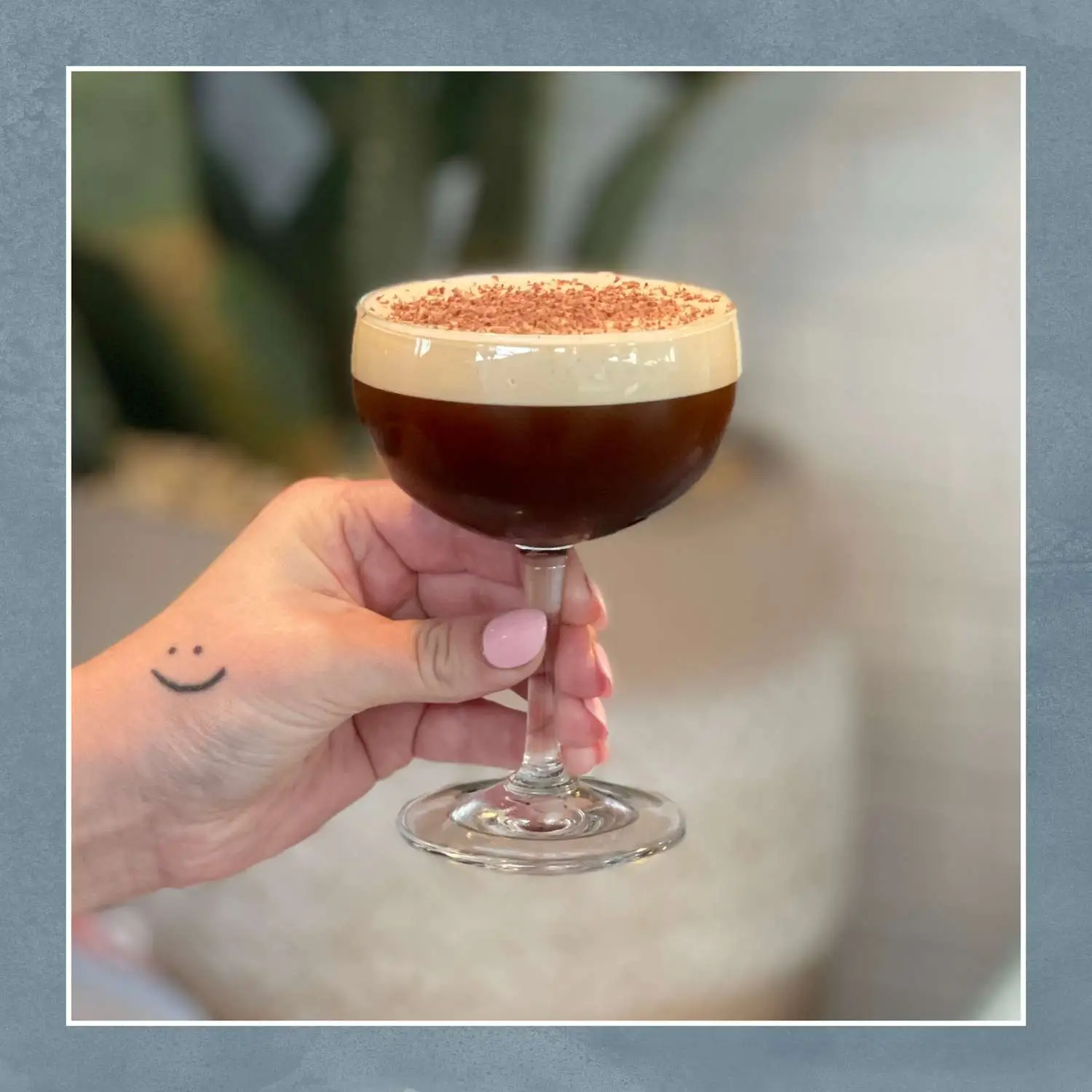 Hand holding coffee cocktail with heavy foam and cinnamon