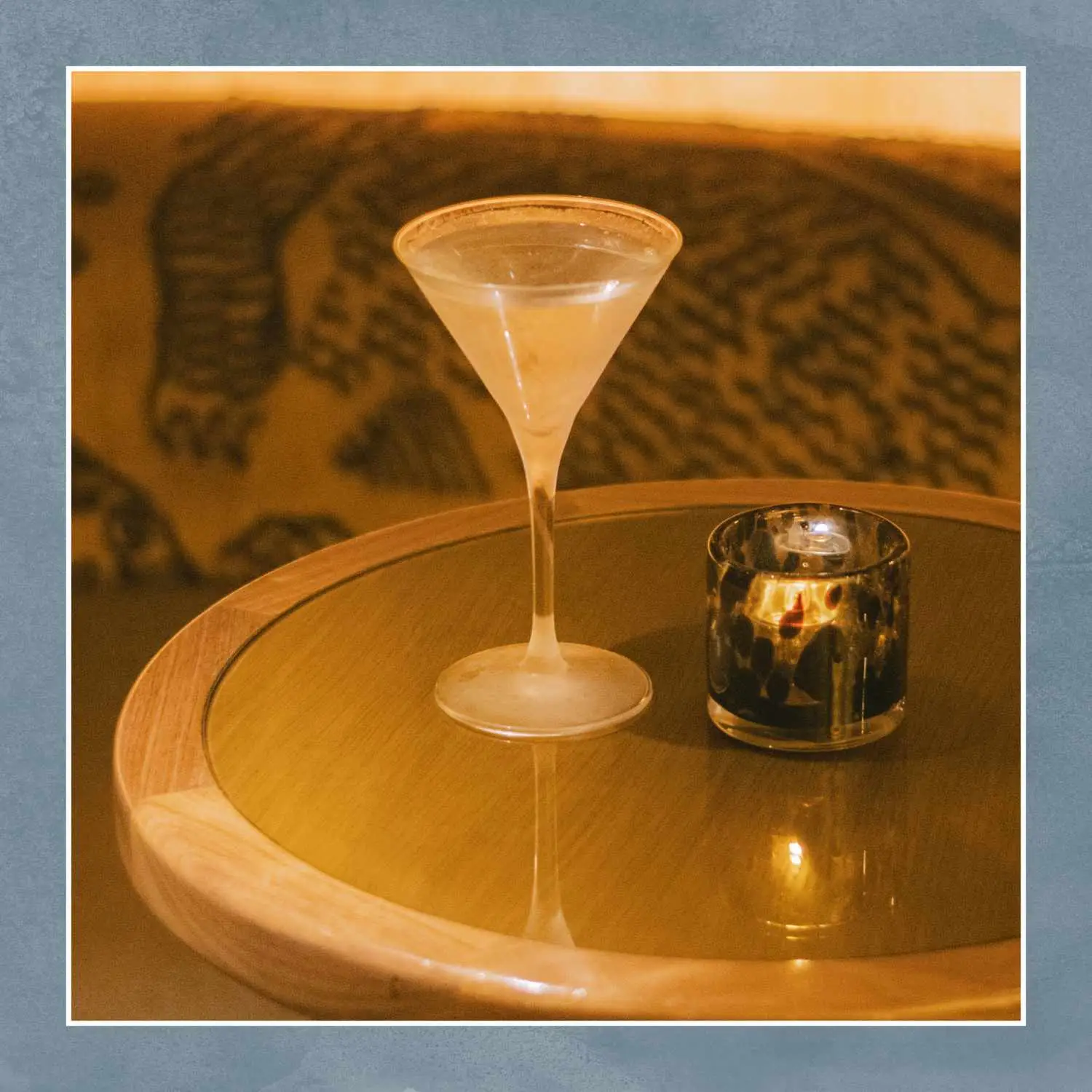Martini in small v shaped glass shot on round table with candle and moody ambience