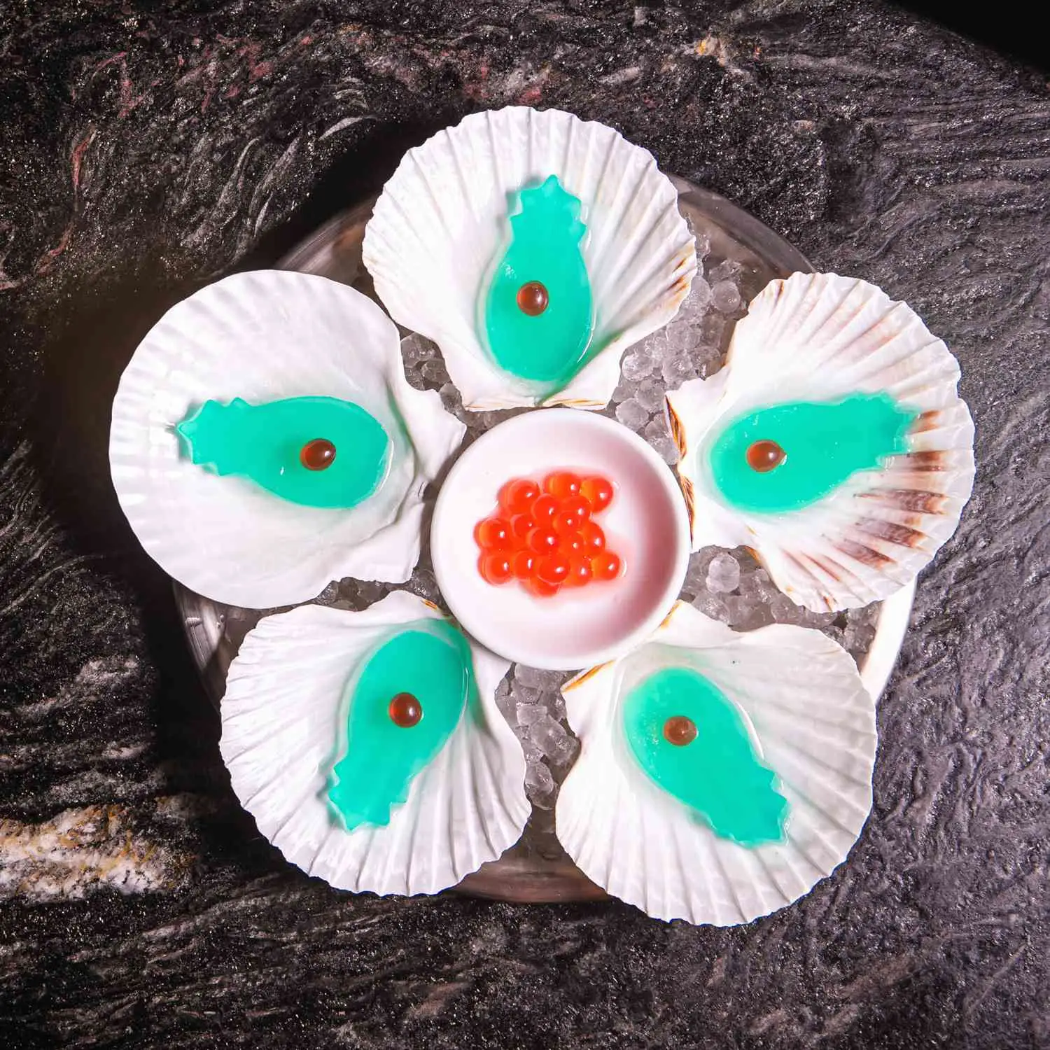 Pineapple-shaped blue jello shots plated inside seashells