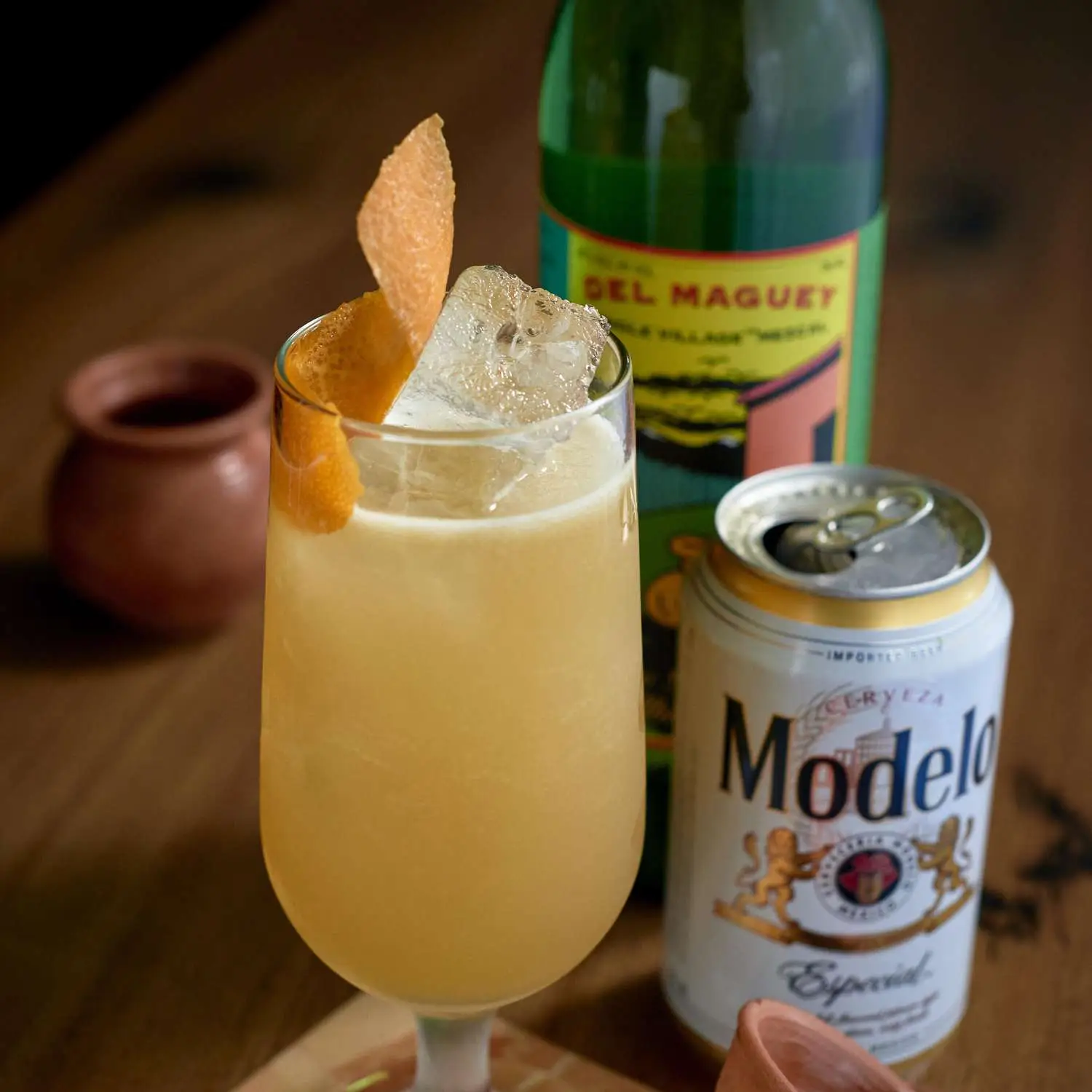 La Botana cocktail in a footed highball with can of Modelo and bottle of Del Maguey mezcal next to it